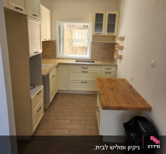 מטבח נקי עם ארונות, משטח עבודה ופח אשפה